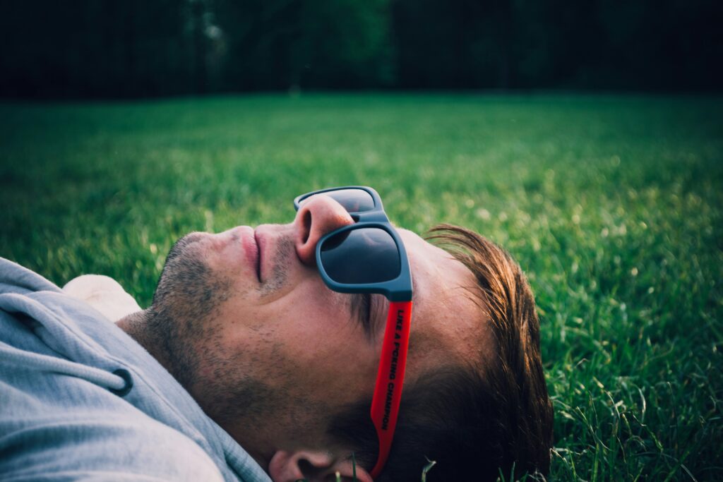 Man with sunglasses on and lying on grass enjoying one of his restdays