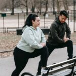 Couple stretching against park bench