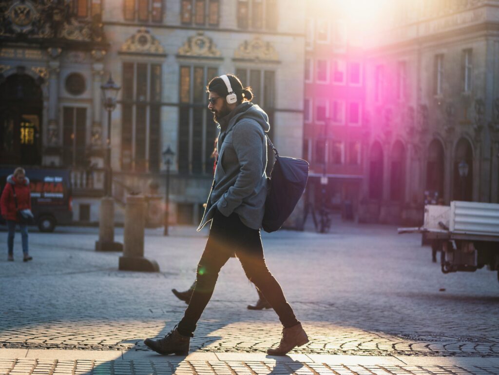 Man in Gray Hooded Jacket Walking on Gray Bricks Pavement